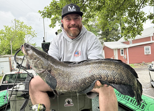 Man sitting on a cooler holding a large fish